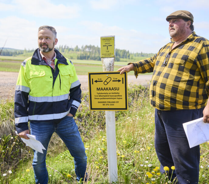 Farmer Aarno Lindfors and Gasgrid's land-use engineer in a field next to a natural gas marker