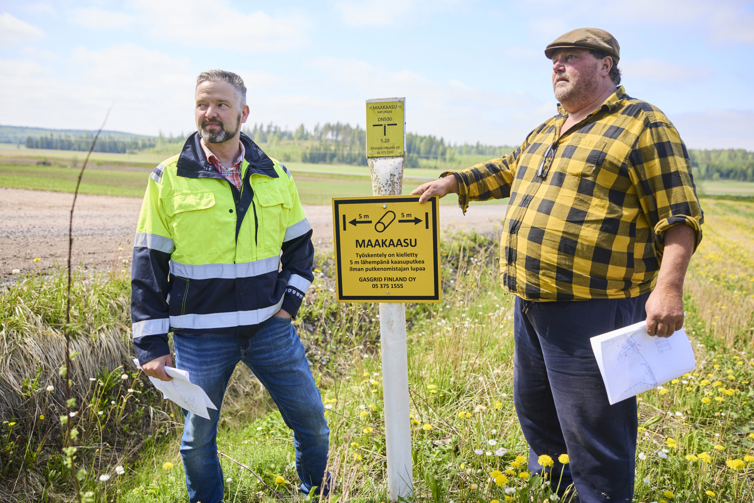 Farmer Aarno Lindfors and Gasgrid's land-use engineer in a field next to a natural gas marker